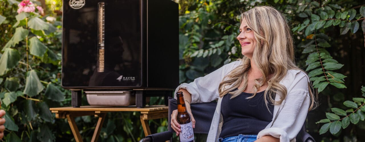 Woman sitting next to the Raven smoker drinking a beer