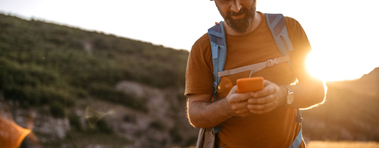 man hiking looking at phone