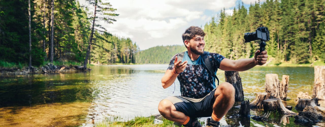 influencer in creek holding camera